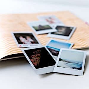 A collection of printed photos ready to be placed in a photo album.