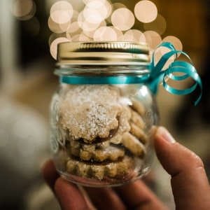 A small glass jar filled with homemade cookies, dusted with sugar for extra sweetness.